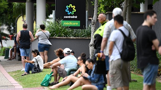 People are seen in long queues outside a Centrelink office.