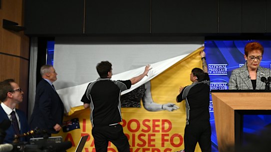 Press Club staff hold up a banner seen behind One Nation leader Pauline Hanson.