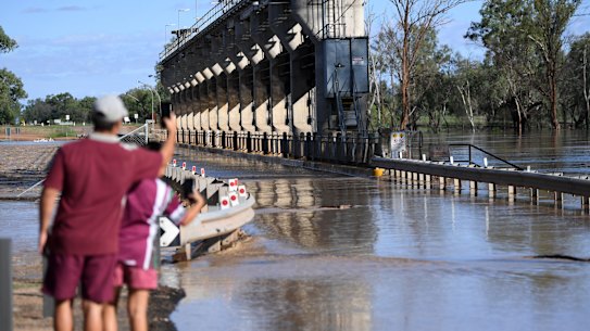 Locals take photos as water from the swollen Balonne river begin to flood the Andrew Nixon bridge in St George, south-western Queensland, Wednesday, February 26, 2020. The river is expected to break its banks and peak over 12 metres on Thursday, causing floods.