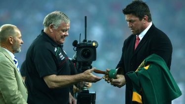 Mark Carroll passes on the bell to Bob McCarthy to ring before the 2014 grand final.
