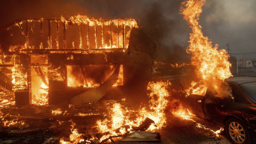 Flames consume a car and building as the Camp Fire tears through Paradise.