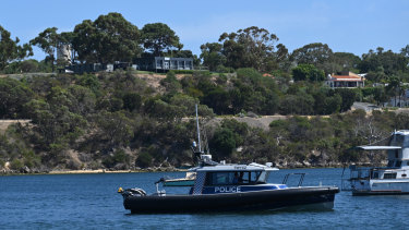 A police boat is patrolling the river at the scene. 