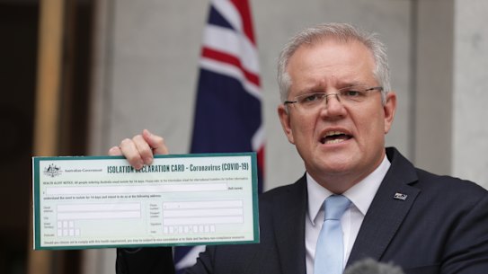 Prime Minister Scott Morrison holds up a Coronavirus Isolation Declaration card.