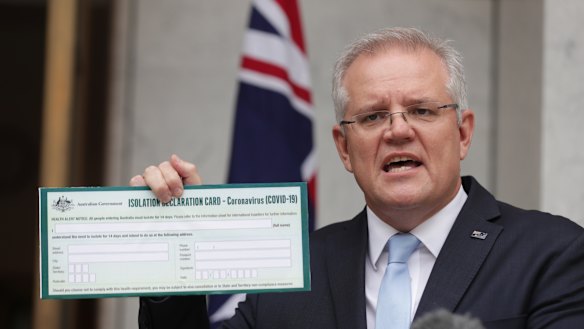 Prime Minister Scott Morrison holds up a coronavirus Isolation Declaration Card.