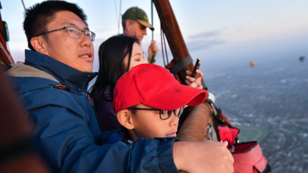 Chinese tourists Wei Chen and Zhu Yi Qi with their son Zhu Si Yun, fly in a hot air balloon over Melbourne.