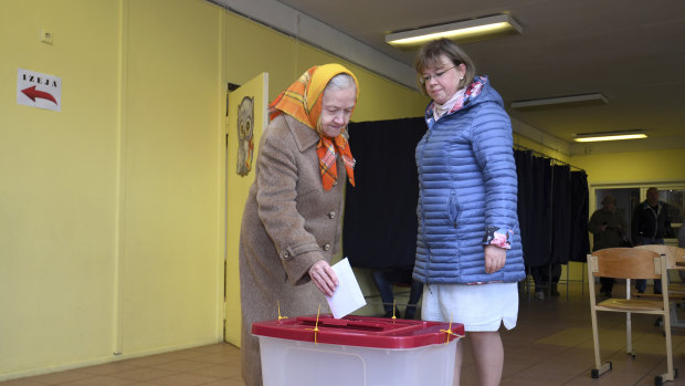 An elderly Latvian woman casts her ballot papers at a polling station in Riga, Latvia, on Saturday.