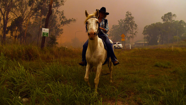 Rhonda Anderson moves herself and her horse to safety near Mount Larcom.