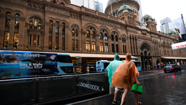 Pedestrians are seen in the CBD during a thunderstorm in Sydney on Saturday