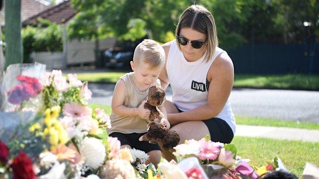 Chantel Taylor and her two year-old son Henley pause after placing teddybears at a makeshift shrine near the scene of the murders.