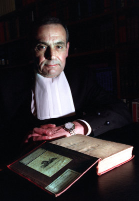 Justice David Levine AO RFD QC, inspects a book originally in the personal library of Charles Dickens.