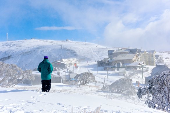 Local skier Drew Jolowicz walks through the snow laden Mt Hotham village on Saturday.