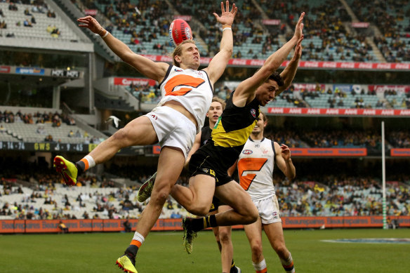 Taken out: Giant Nick Haynes cops a knock from Tigers' Jason Castagna.