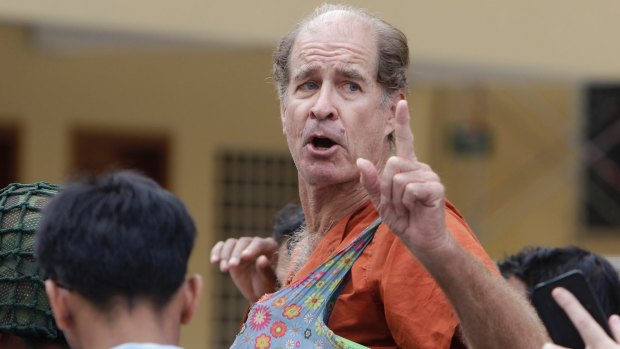 Australian filmmaker James Ricketson gestures as he is escorted by prison guards at the Cambodian Supreme Court in Phnom Penh, Cambodia.