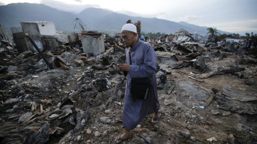 A man walks by remains of toppled houses at the earthquake damaged neighbourhood of Balaroa in Palu.