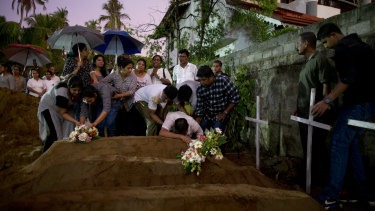 Relatives place flowers after the burial of three victims of the same family who died at Easter Sunday bomb blast at St Sebastian Church in Negombo.