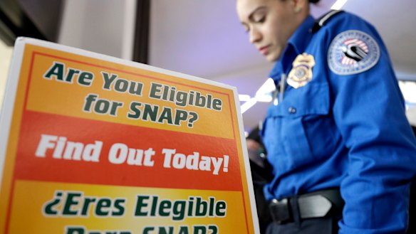 A Transportation Security Administration employee stands at a booth to learn about a food stamp program at Newark Liberty International Airport, which has been affected by the government shutdown. 