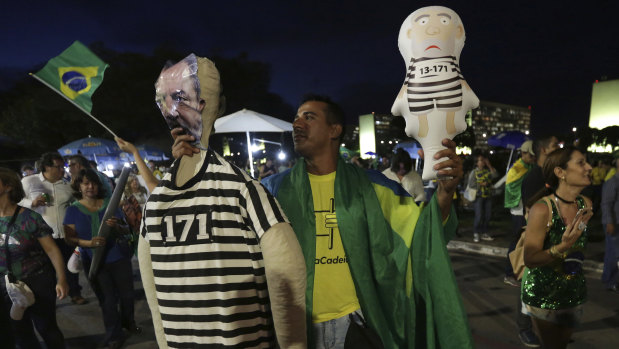 A anti-Lula protester holds Lula-like dolls dressed as inmates in Brasilia.