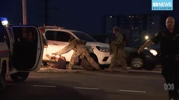 Police arrest a man in Darwin on Tuesday after four people were shot dead and one was injured.