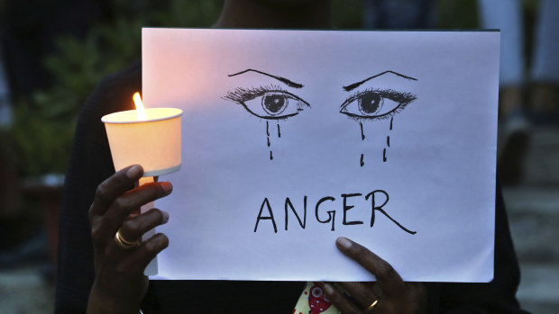 A woman holds a candle and placard seeking an end to sexual violence against women during a protest in Bangalore.