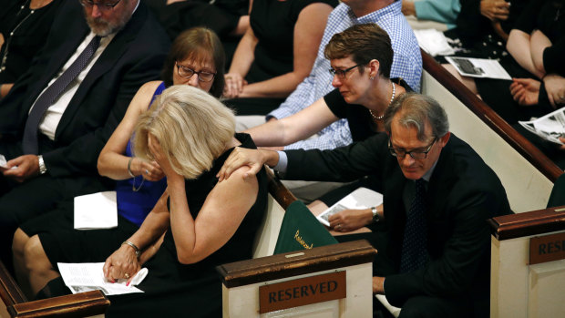 Andrea Chamblee, bottom left, is comforted during a memorial service for her husband John McNamara.