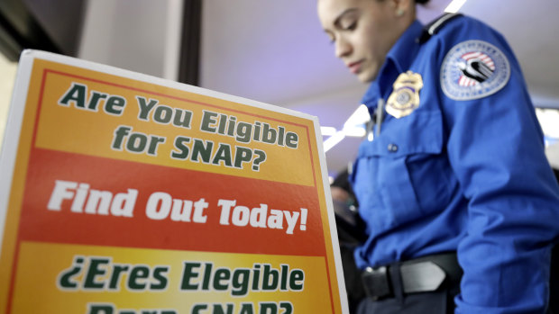 A Transportation Security Administration employee stands at a booth to learn about a food stamp program.