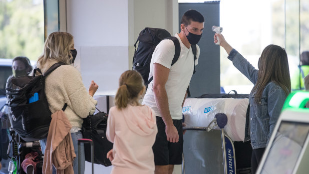 Carlton's Matthew Kreuzer - with his family - undergoes a temperature check at Melbourne Airport before leaving for the AFL's transition hub on Thursday. 