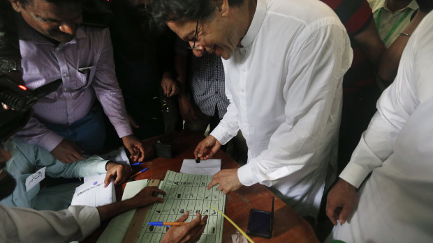 Imran Khan, centre, casts his vote in front of the cameras.