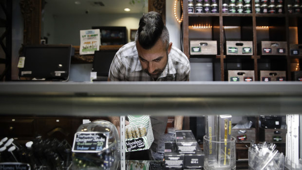 Jerred Kiloh, owner of the Higher Path medical marijuana dispensary, stocks shelves with with cannabis products in Los Angeles.
