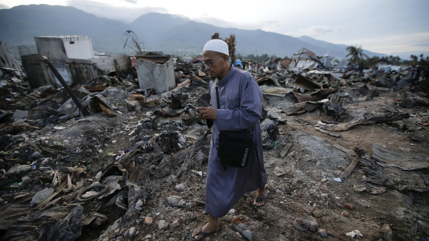 A man walks by remains of toppled houses at the earthquake damaged neighbourhood of Balaroa in Palu.