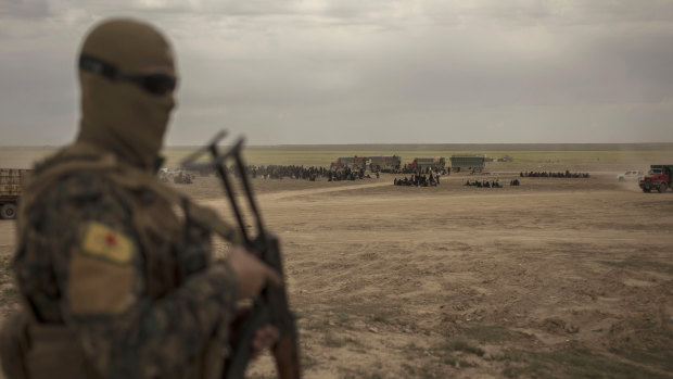 A member of US-backed Syrian Democratic Forces stands guard at a reception area for people evacuated from the last shred of territory held by Islamic State militants, outside Baghouz, Syria.