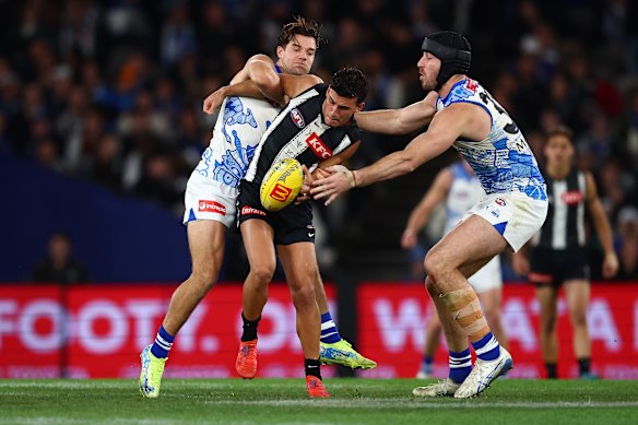 Jy Simpkin of the Kangaroos tackles Nick Daicos of the Magpies.