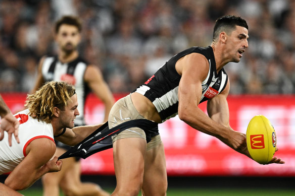 Scott Pendlebury of the Magpies passes is tackled by James Rowbottom of the Swans.