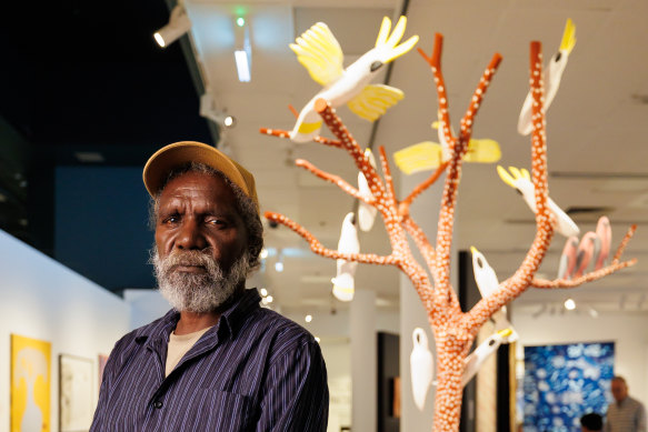 Keith Wikmunea with his work Ku’, Theewith & Kalampang: The White Cockatoo, Galah and the Wandering Dog.