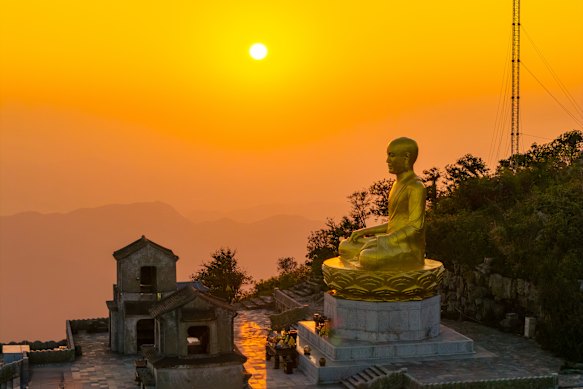 Sunset frames a golden statue of Buddha on Yen Tu Mountain, Vietnam. 