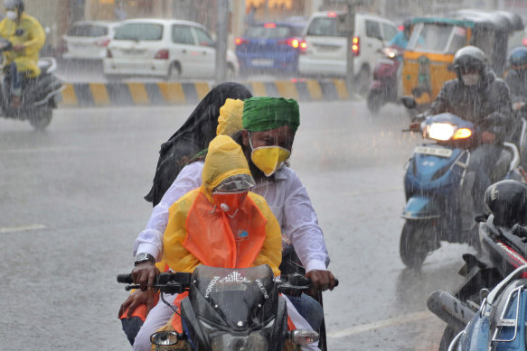 An Indian family wearing face masks navigates monsoon rains in Hyderabad, India.