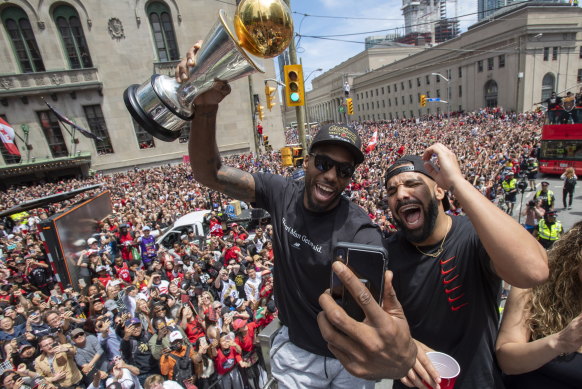 Kawhi Leonard (holding his MVP trophy) and Drake celebrate Toronto's NBA success at the parade.