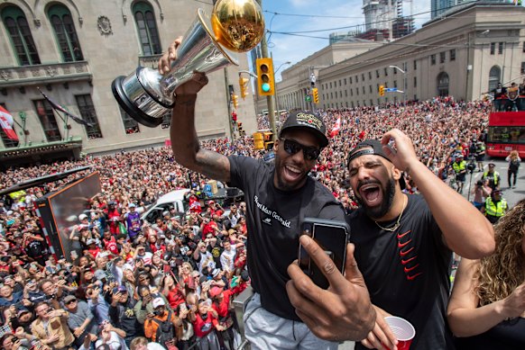 Kawhi Leonard (holding his MVP trophy) and Drake celebrate Toronto's NBA success at the parade.