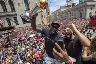 Kawhi Leonard (holding his MVP trophy) and Drake celebrate Toronto's NBA success at the parade.