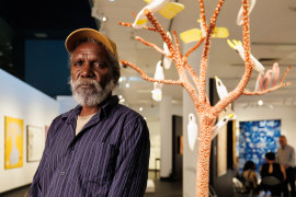 Keith Wikmunea with his work Ku’, Theewith & Kalampang: The White Cockatoo, Galah and the Wandering Dog.