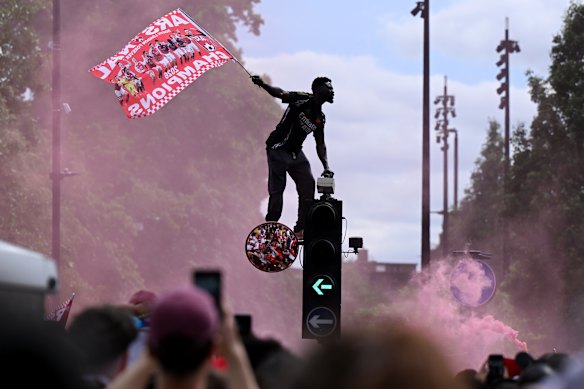An Arsenal fan waves a flag on top of a traffic light during the Arsenal Trophy Parade on May 31, 2026 in Islington, England. Arsenal clinched their first Premier League title in 22 years earlier this month.