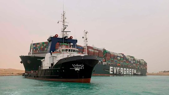 A boat navigates in front of the wedged cargo ship Ever Given.