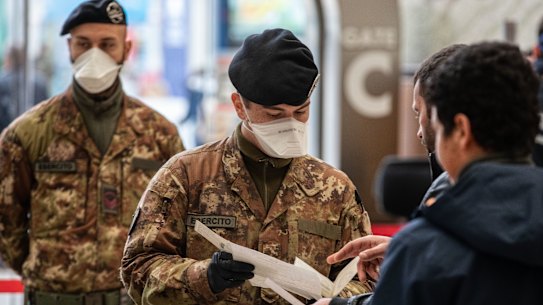 Italian soldiers process passengers leaving from Milano Centrale train station.