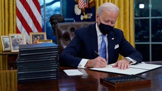 President Joe Biden signs his first executive orders in the Oval Office of the White House.