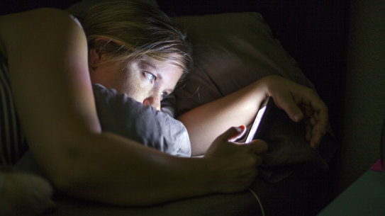 Woman using phone in bed. 