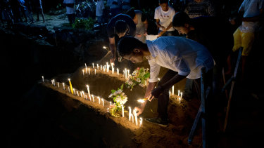 Relatives light candles after the burial of three victims from the same family who died at St Sebastian Church in Negombo, Sri Lanka.