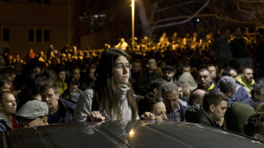 A protester stands as a crowd gathers at an entrance to the state-run TV headquarters in Belgrade, Serbia, on Saturday.