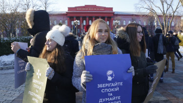 Students hold posters reading "Keep calm and think with your head" and "Keep calm support the army" in front of a university in Kiev, Ukraine, after Russia seized the crew of three Ukrainian vessels.