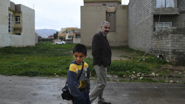 Ayham Azad walks with his uncle Tahsin Shahwan, who cares for him and his brother.