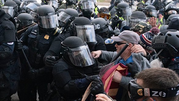 Capitol police officers in riot gear push back demonstrators who try to break a door of the US Capitol on January 6.