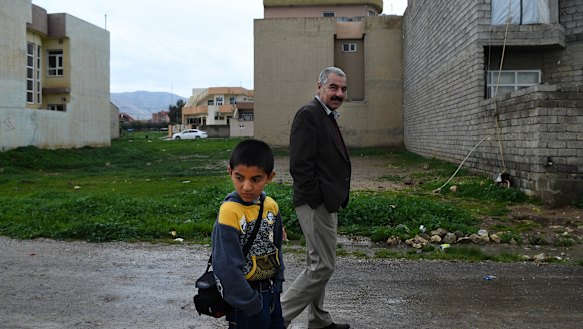 Ayham Azad walks with his uncle Tahsin Shahwan, who cares for him and his brother.
